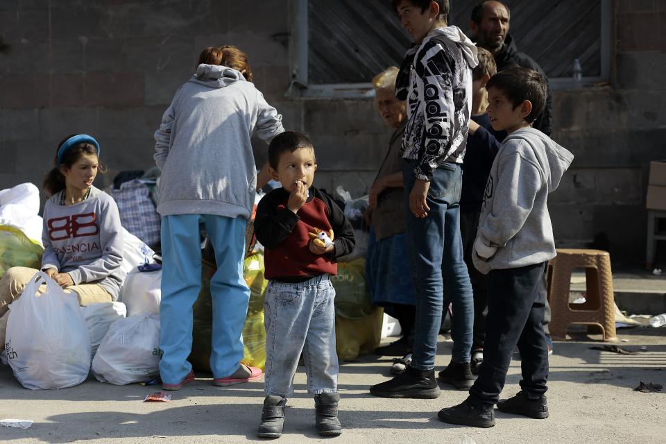 Ethnic Armenians from Nagorno-Karabakh gather next to their belongings near a tent camp after arriving to Armenia's Goris in Syunik region, Armenia, on Saturday, Sept. 30, 2023. Armenian officials say that by Friday evening over 97,700 people had left Nagorno-Karabakh. The region's population was around 120,000 before the exodus began. (AP Photo/Vasily Krestyaninov)