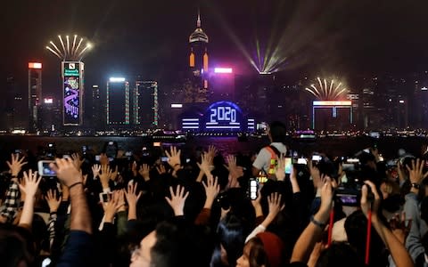 Protesters hold up their hands to symbolize the five demands of the pro-democracy movement as New Year's fireworks light up the sky in Hong Kong - Credit: AP