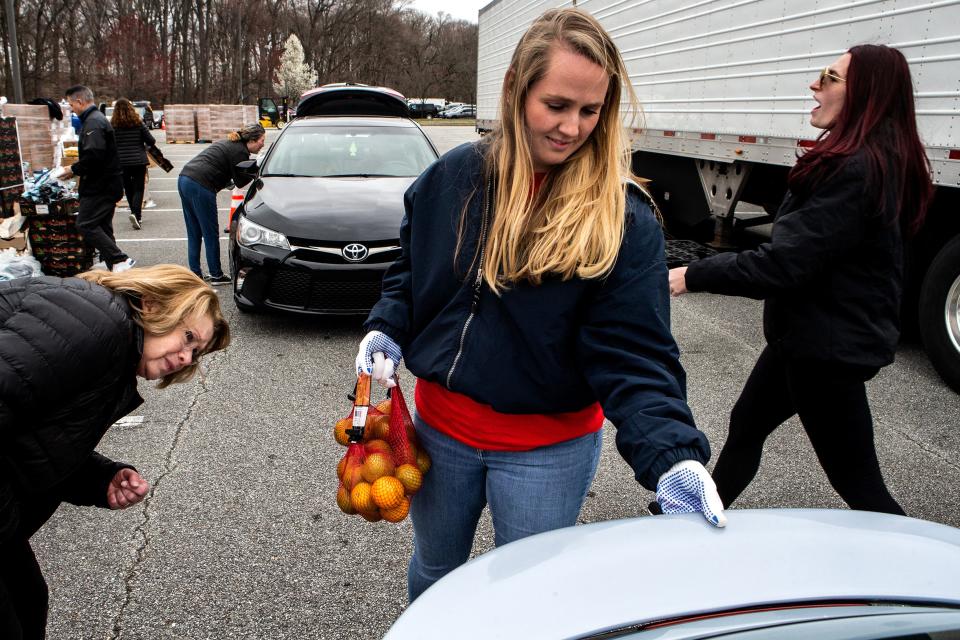 Volunteer Caroline Franchino, at center, distributes bags of oranges at the Delaware Food Bank's drive-thru event at Delaware Community Technical College in Stanton on Friday, March 31, 2023. There was a high turnout at the event due to the expiration of the COVID-19 pandemic emergency SNAP benefits.