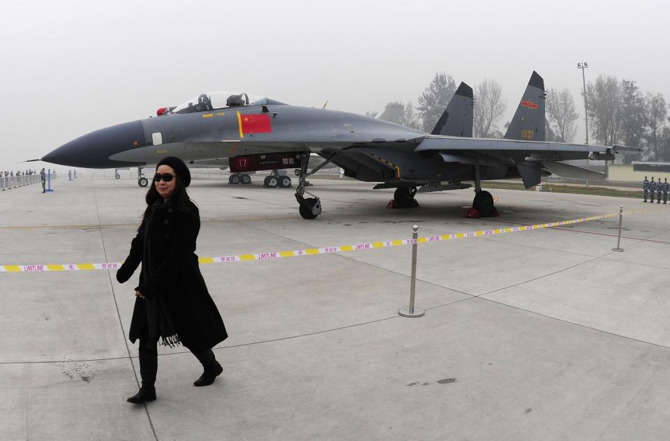 FILE - In this Nov. 8, 2009, file photo, a woman walks near a Chinese People's Liberation Army Air Force's J-11 fighter jet displayed for the Air Force's 60th anniversary at an airport in Beijing, China. Taiwan says its planes warned off Chinese military aircraft that crossed the center line in the Taiwan Strait, calling China’s move a provocation that seeks to alter the status quo in the waterway dividing the island from mainland China.(AP Photo, File)