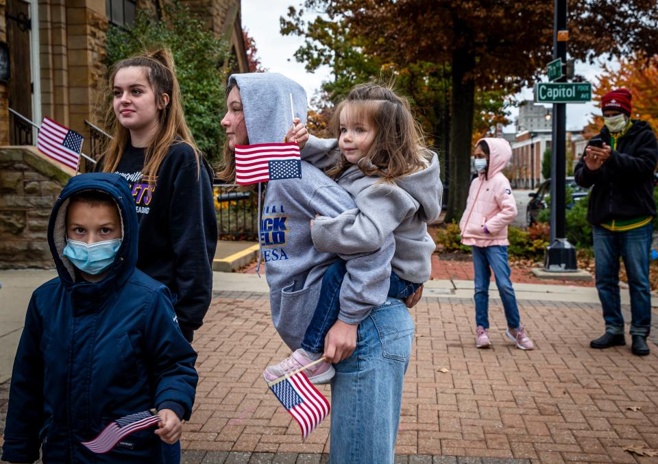 Eva Hollinshead, 2, hitches a ride on the back of her sister, Alex Hollinshead, 12, as she waves her American Flag during the Veterans Day Parade along Capitol Avenue in Springfield, Ill., Thursday, November 11, 2021. [Justin L. Fowler/The State Journal-Register] 