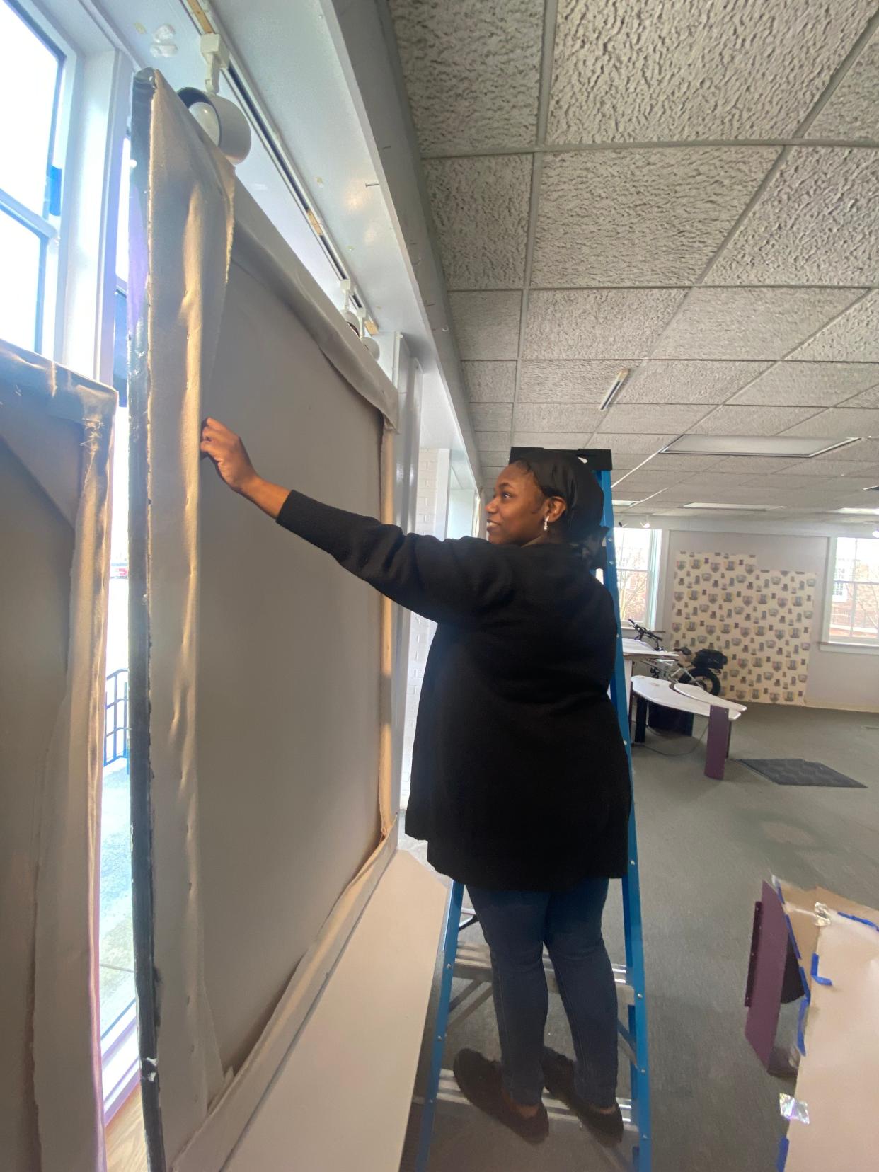 Denison University junior Renai Heath hangs a piece of her artwork instead the former retail space inside Granville Village Hall. Heath's work, along with work from other Denison students, will be displayed temporary inside the space.