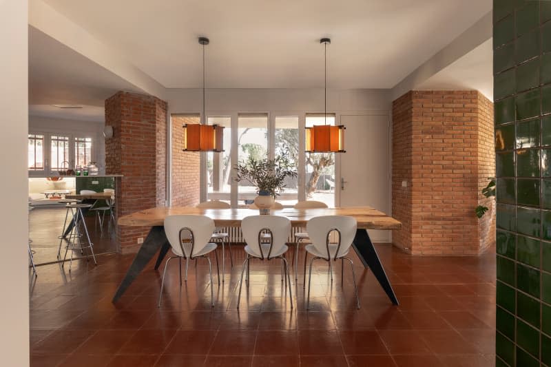 Pendant lamps hung over dining room in airy, open home.