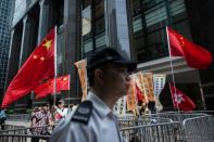 A policeman walks past pro-China supporters in Hong Kong on May 18, 2016, during the second day of a visit by China's National People's Congress (NPC) Standing Committee Chairman Zhang Dejiang