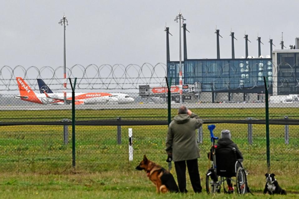 Schaulustige stehen am Zaun der Südbahn nahe dem Tower vom Hauptstadtflughafen BER.<span class="copyright">Patrick Pleul / dpa</span>