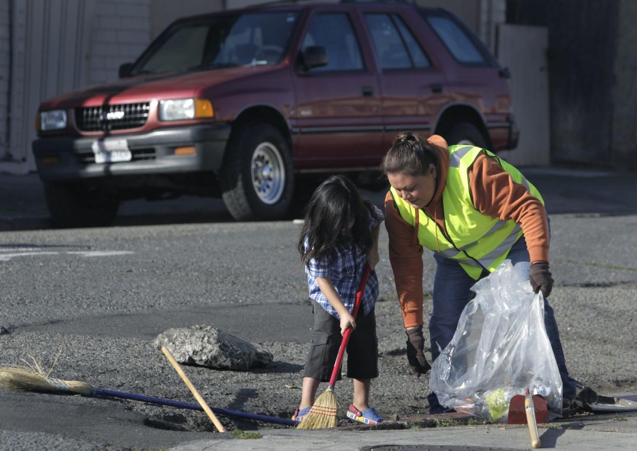 veronica tril right removes trash and debris from a storm drain with her son timmy, 4, near their 36th avenue home in oakland, calif on saturday, jan 4, 2014 the city of oakland is encouraging residents to adopt storm drains in their neighborhood to