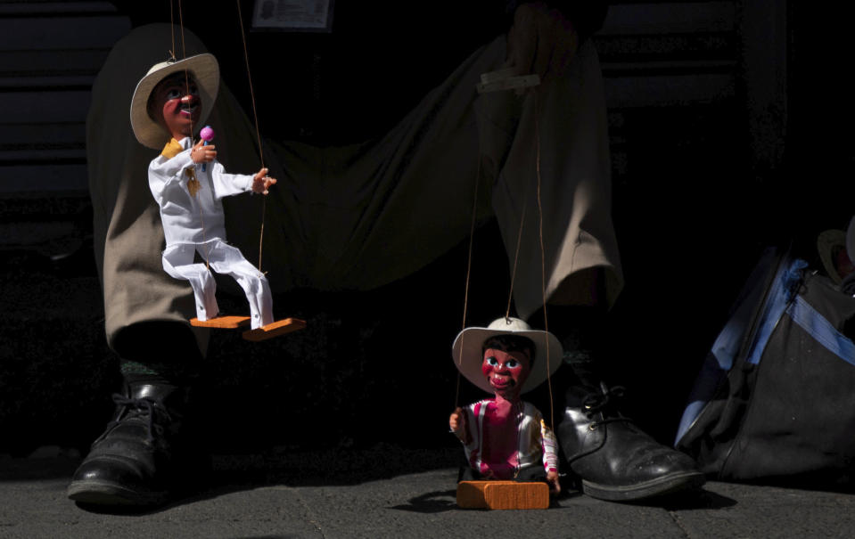 An artisan sells marionettes on the sidewalk in downtown Mexico City, Friday, July 10, 2020. After three months of the economic shutdown to contain the spread of COVID-19, the city has partially reopened some commercial areas, including downtown. (AP Photo/Fernando Llano)