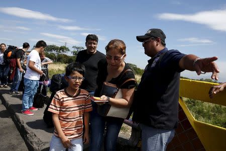 A Venezuelan border official, allows access into Venezuela to a family, after he checks their IDs, while they cross the Simon Bolivar bridge on the border with Colombia, at San Antonio in Tachira state, Venezuela, August 26, 2015. REUTERS/Carlos Garcia Rawlins