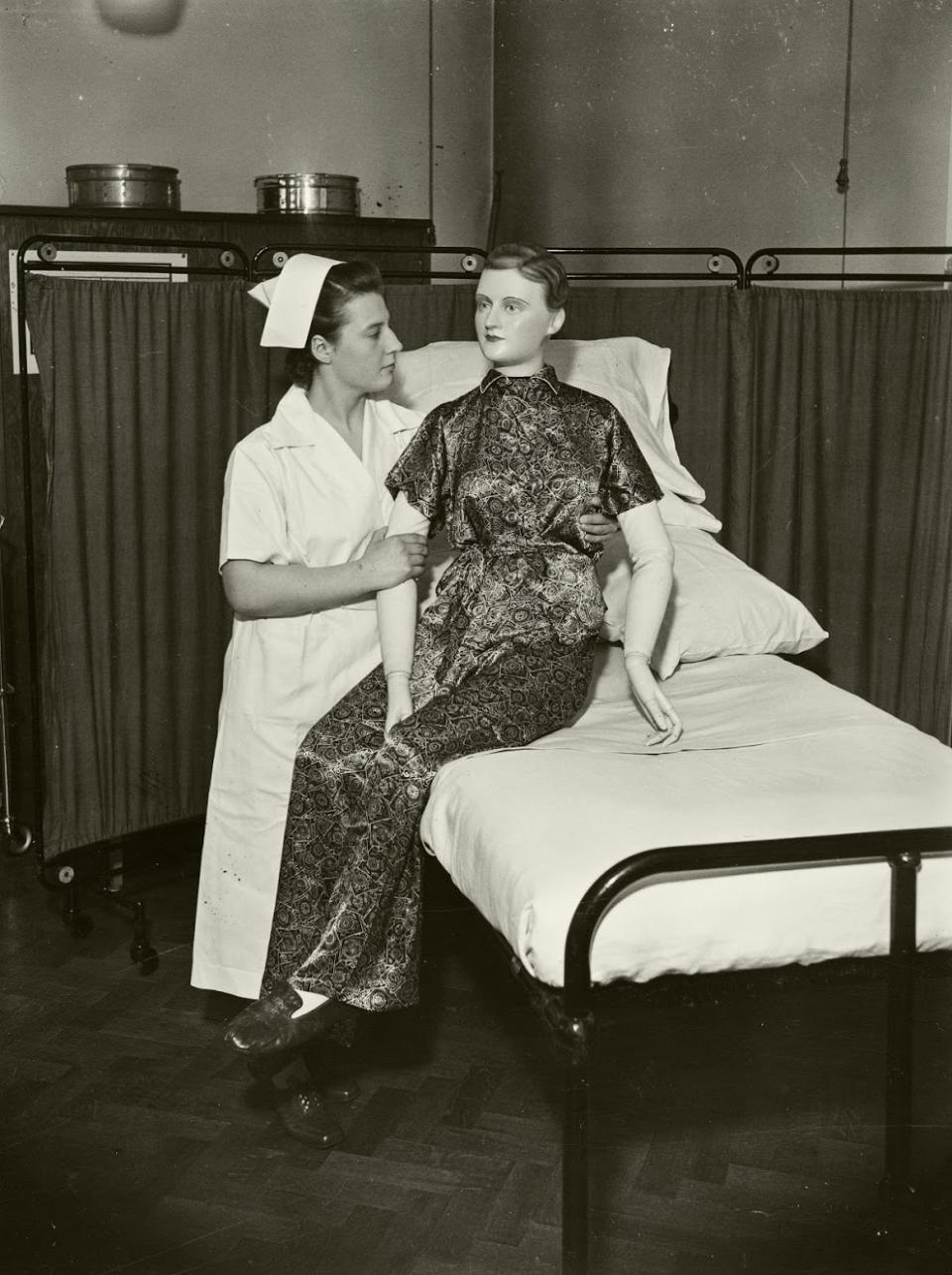 A student nurse using a jointed model patient to practise assisting a patient to get out of bed, in the Preliminary Training School at Central Middlesex County Hospital