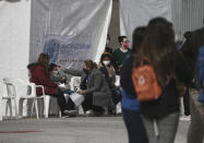 A member of the International Organization for Migration takes a child's temperature before crossing the border into El Paso, Texas at the Leona Vicario shelter in Ciudad Juarez, Mexico, Friday, Feb. 26, 2021. After waiting months and sometimes years in Mexico, people seeking asylum in the United States are being allowed into the country as they wait for courts to decide on their cases, unwinding one of the Trump administration's signature immigration policies that President Joe Biden vowed to end. (AP Photo/Christian Chavez)