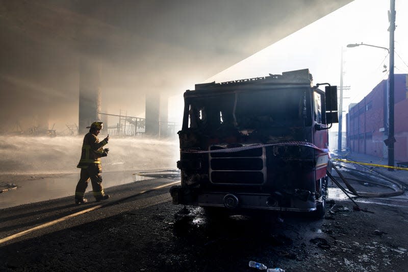 Burnt down firetruck underneath I10 Freeway in Los Angeles. Firefighter approaching from left side. smoke billowing.