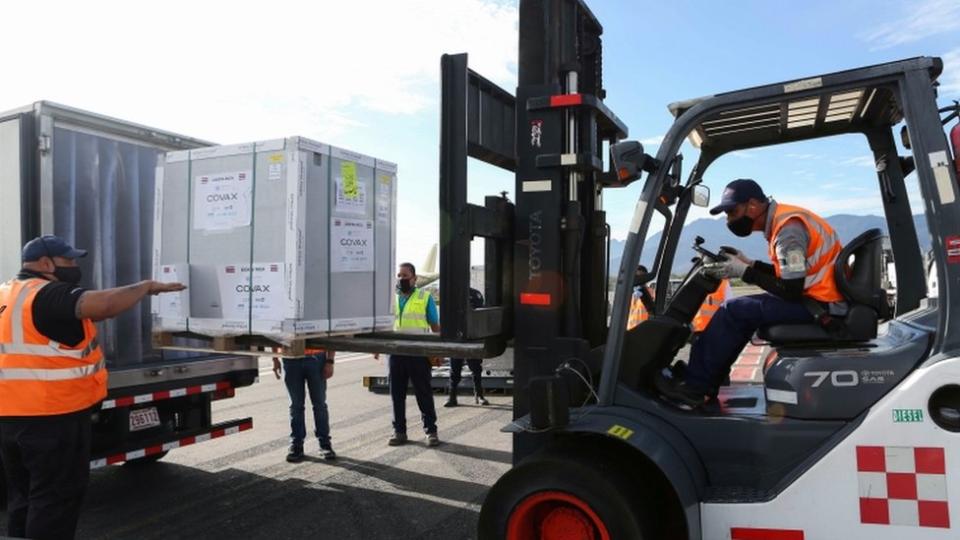 Trabajadores descargan un container con vacunas de AstraZeneca.