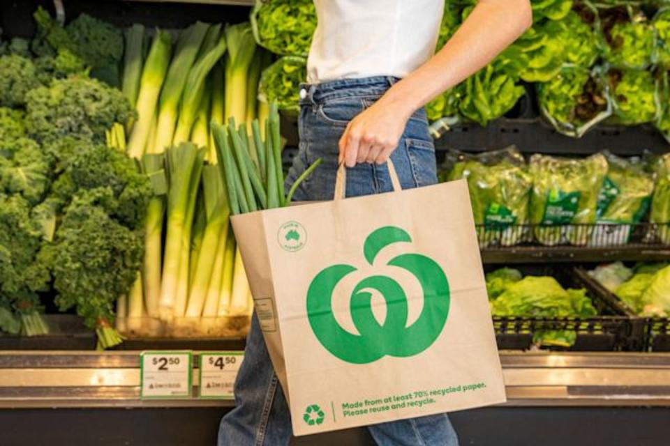 Female Woolworths customer carries paper bag in store