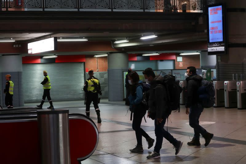 People walk by Atocha train station as members of the Military Emergency Unit (UME) patrol during partial lockdown as part of a 15-day state of emergency to combat the coronavirus (COVID-19) spread in Madrid