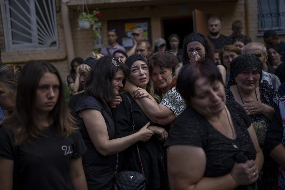 Familiares y amigos tratan de consolar a Anastasia Ohrimenko, de 26 años, mientras lamenta la pérdida de su esposo, Yury Styglyuk, un militar ucraniano que murió en combate el 24 de agosto en Maryinka, Donetsk, durante su funeral en Bucha, Ucrania, el 31 de agosto de 2022. (AP Foto/Emilio Morenatti)