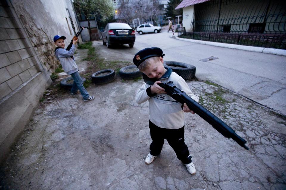 Ukrainian boys play with a toy gun in Simferopol, Crimea, Tuesday, March 25, 2014. (AP Photo/Pavel Golovkin)