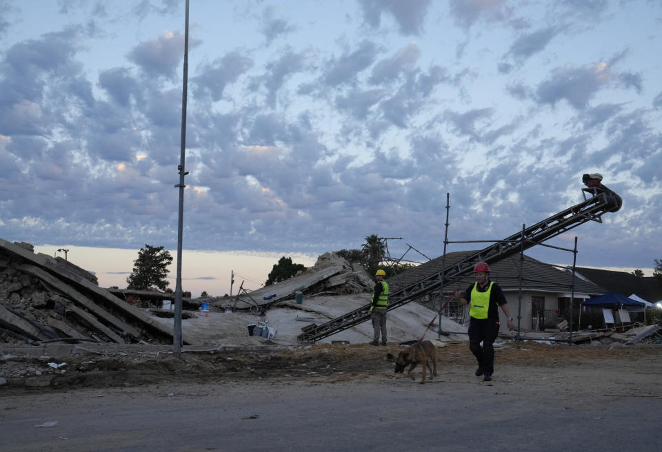 A rescue worker walks with a sniffer dog at the site of a building collapse in George, South Africa, Wednesday, May 8, 2024. Rescue operations continue for dozens of construction workers missing. (AP Photo/Nardus Engelbrecht)