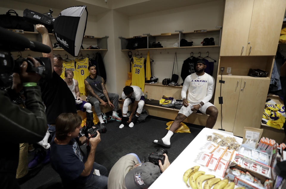 Los Angeles Lakers forward LeBron James, right, sits in the locker room before an NBA preseason basketball game against the Denver Nuggets Sunday, Sept. 30, 2018, in San Diego. (AP Photo/Gregory Bull)