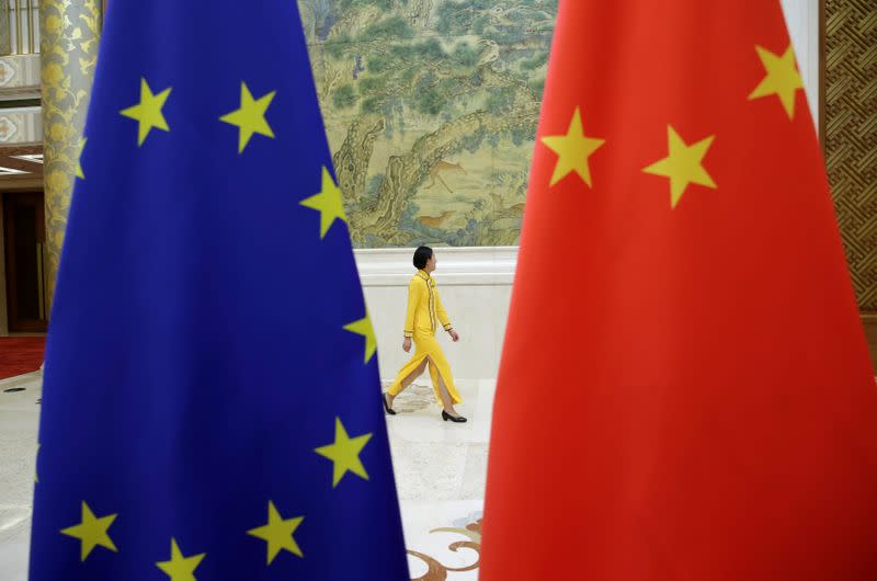 FILE PHOTO: An attendant walks past EU and China flags ahead of the EU-China High-level Economic Dialogue in Beijing