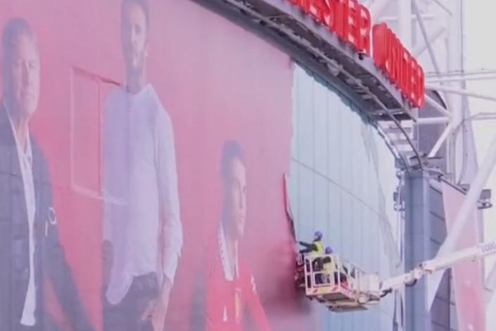 Operarios con una grúa remueven la gigantografía de Cristiano Ronaldo en Old Trafford, el estadio de Manchester United