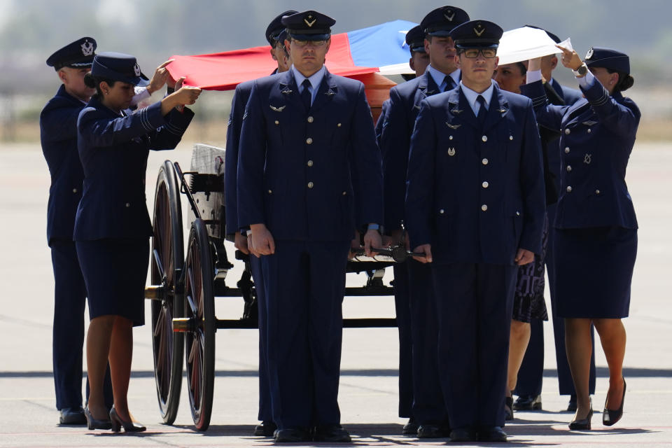 Officials place a Chilean flag on the casket of former Chilean President Sebastian Pinera after his remains arrived at the airport in Santiago, Chile, Wednesday, Feb. 7, 2024. The two-time former president died on Feb. 6 in a helicopter crash. He was 74. (AP Photo/Esteban Felix)