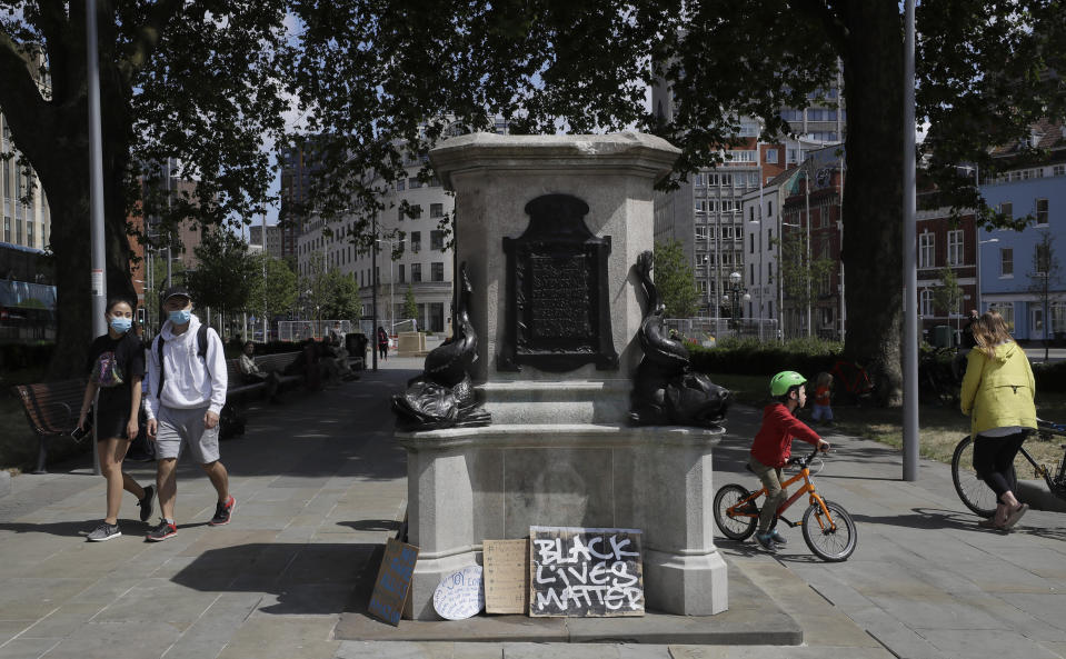 People look at the pedestal of the toppled statue of Edward Colston in Bristol, England, Monday, June 8, 2020, following the downing of the statue on Sunday at a Black Lives Matter demo. The toppling of the statue was greeted with joyous scenes, recognition of the fact that he was a notorious slave trader — a badge of shame in what is one of Britain’s most liberal cities. (AP Photo/Kirsty Wigglesworth)