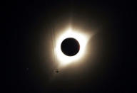 A jet plane flies by the total solar eclipse in Guernsey, Wyoming U.S. August 21, 2017. REUTERS/Rick Wilking