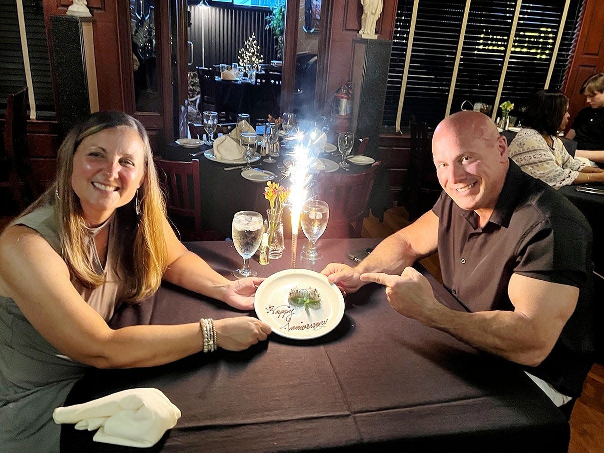 ryan crawley and his wife sitting at a dinner table with an anniversary plate between them