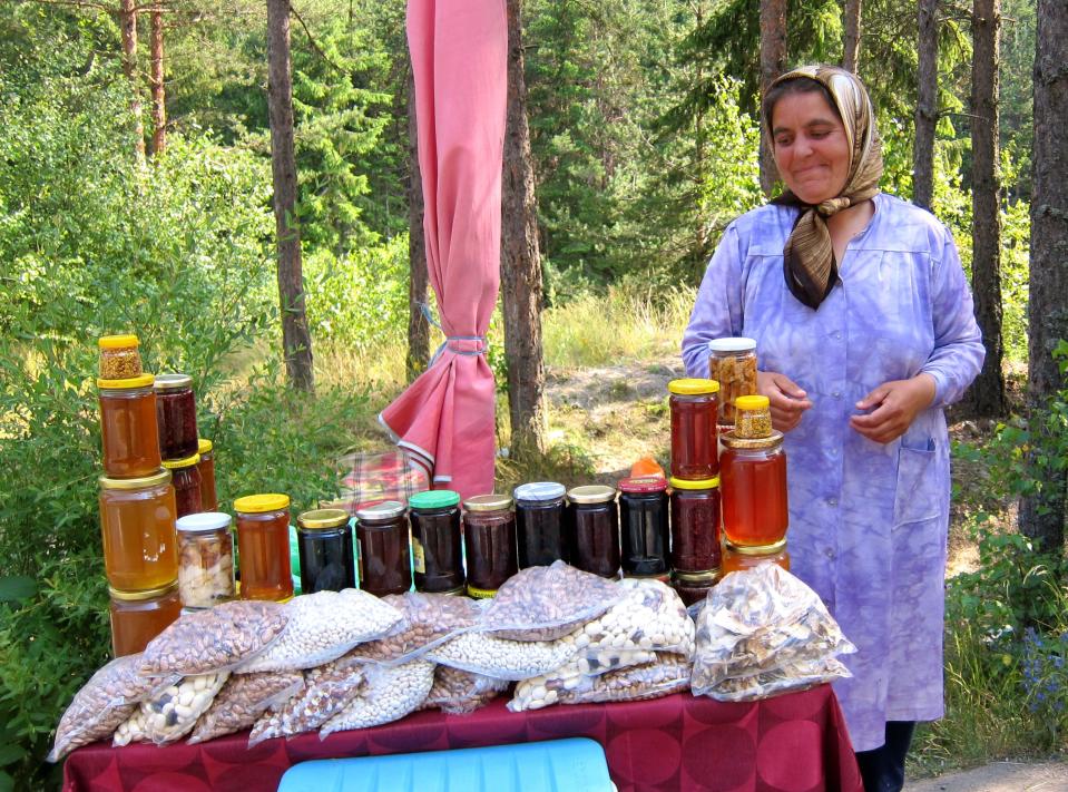 This July 15, 2011 photo shows a woman selling honey at a roadside stand in Bulgaria. A visit to Bulgaria can alternately feel like taking like a step back in time and witnessing a society that has modernized at warp speed. Mules and Ferraris share the freeways. Near a store selling Prada and Versace clothes, old women peddle handmade crocheted doilies and embroidered tablecloths. Dilapidated Soviet-style apartment buildings teem with people, as does a sparkling new shopping mall. (AP Photo/Coralie Carlson)