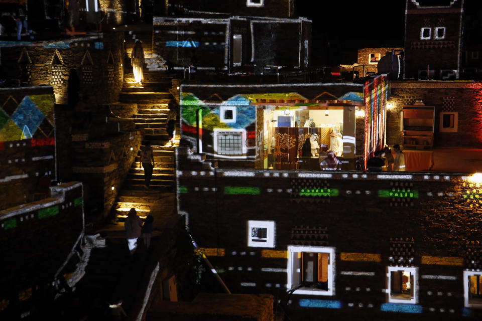 In this Friday, Aug. 23, 2019 photo, a light show is displayed on 500-year-old distinct natural clay, stone and wood structures in the ancient village of Rijal Almaa, during the al-Soudah festival in Abha, southwest Saudi Arabia. A festival atop a chain of mountains drew a medley of yoga enthusiasts, extreme adventure seekers, tourists and traditional Saudi families as the kingdom looks for ways to revamp its image and build up tourism. (AP Photo/Amr Nabil)