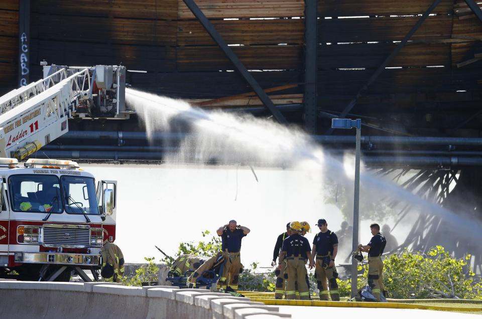 Local firefighters attempt to put out a fire on a derailed freight train on a bridge spanning Tempe Town Lake Wednesday, July 29, 2020, in Tempe, Ariz. Officials say a freight train traveling on the bridge that spans a lake in the Phoenix suburb has derailed, setting the bridge ablaze and partially collapsing the structure. (AP Photo/Ross D. Franklin)