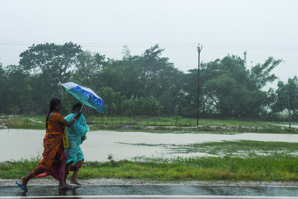 Two women walk with an umbrella under the rain ahead of the expected landfall of cyclone Amphan in Midnapore, West Bengal, on May 20, 2020. (Photo by DIBYANGSHU SARKAR/AFP via Getty Images)