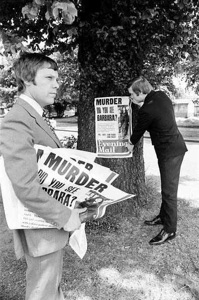 Two men in suits post "MURDER: DO YOU SEE BARBARA?" flyers on a tree