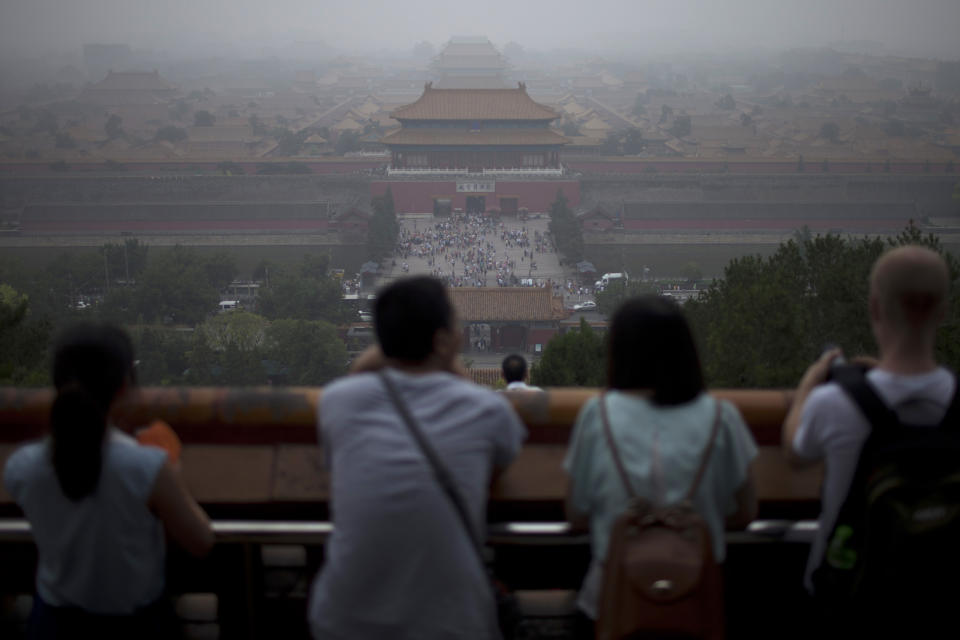 In this photo taken on June 29, 2013, tourists look at the Forbidden City from the top of Jinshan hill on a hazy day in Beijing, China. China’s tourism industry has grown at a fast pace since the country began free market-style economic reforms three decades ago. However, it's latest tourism slogan "Beautiful China" has been derided as particularly inept at a time when record-busting smog has drawn attention to the environmental and health costs of China’s unfettered industrialization. Some point to unsophisticated marketing as an explanation. (AP Photo/Alexander F. Yuan)