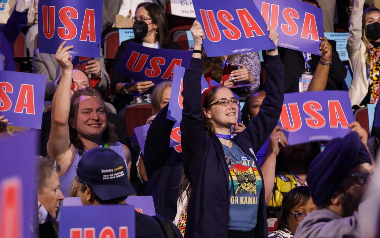 Attendees hold USA signs during the first day of the Democratic National Convention