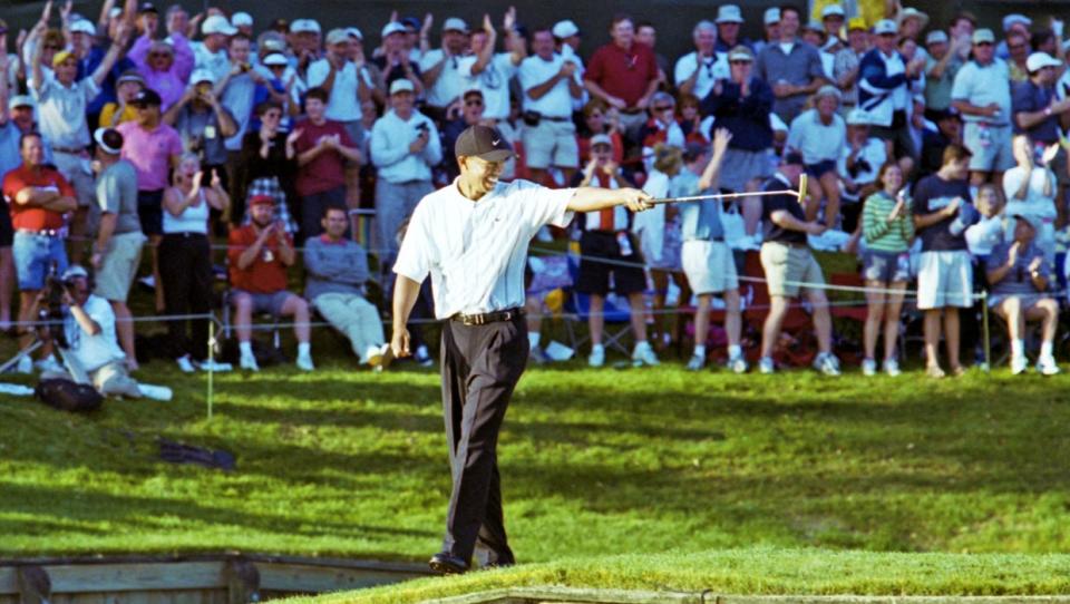Tiger Woods points his putter at playing partner Phil Mickelson from the walkway to the green after sinking a 60-foot birdie putt at the 17th hole of the TPC Sawgrass Players Stadium Course on March 24, 2001, in the third round of The Players Championship. Woods went on to win the tournament two days later in a Monday finish. [Bob Self/Florida Times-Union]