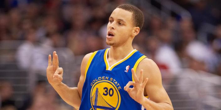 Stephen Curry holds up three fingers on both hands while running down the court during a game in 2011.