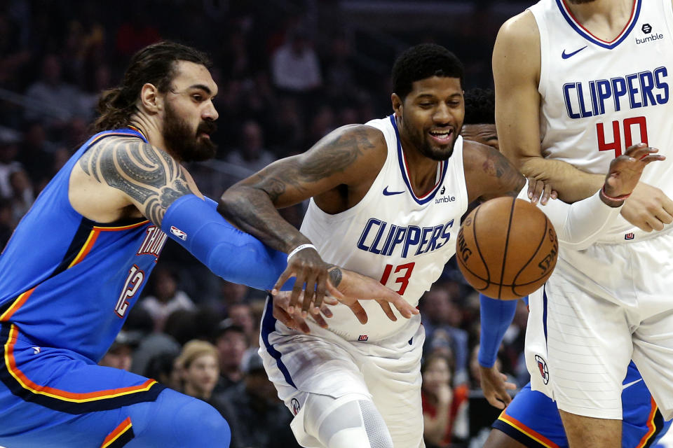 Los Angeles Clippers' Paul George (13) and Oklahoma City Thunder's Steven Adams (12) fight for a ball during the first half of an NBA basketball game, Monday, Nov. 18, 2019, in Los Angeles. (AP Photo/Ringo H.W. Chiu)