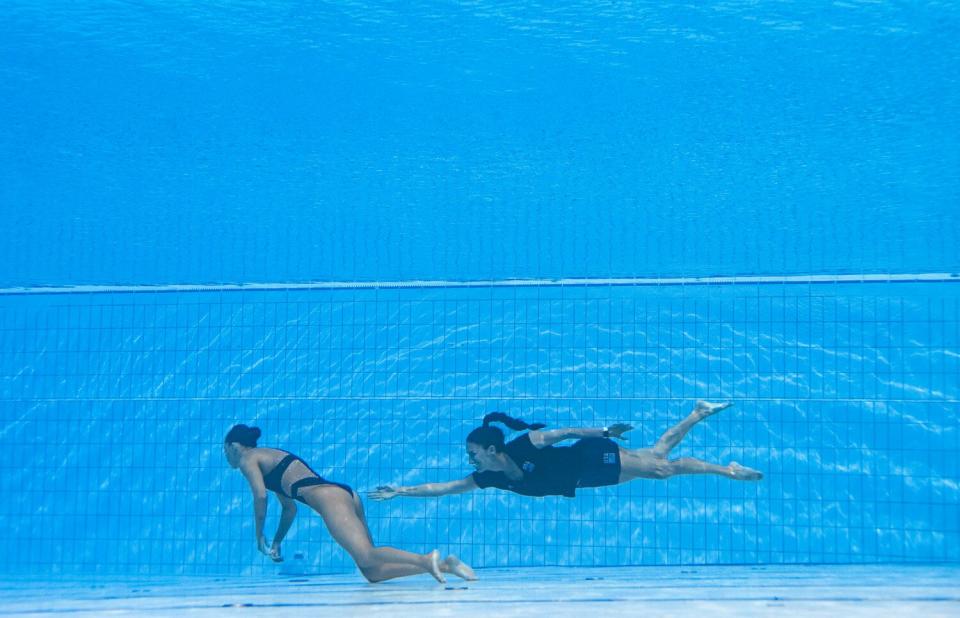 A member of Team USA (R) recovers USA's Anita Alvarez (L), from the bottom of the pool during an incident in the women's solo free artistic swimming finals, during the Budapest 2022 World Aquatics Championships