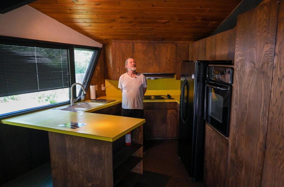 Lantz Stephenson stands in the mostly-original kitchen of the home which features bright yellow counter tops.