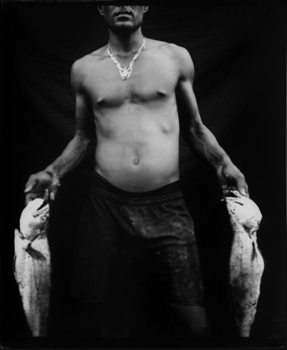 Ionervis Gonzales poses for a portrait holding part of his catch after a day of working in oil-contaminated Lake Maracaibo in Cabimas, Venezuela. (Photo: Rodrigo Abd/AP)