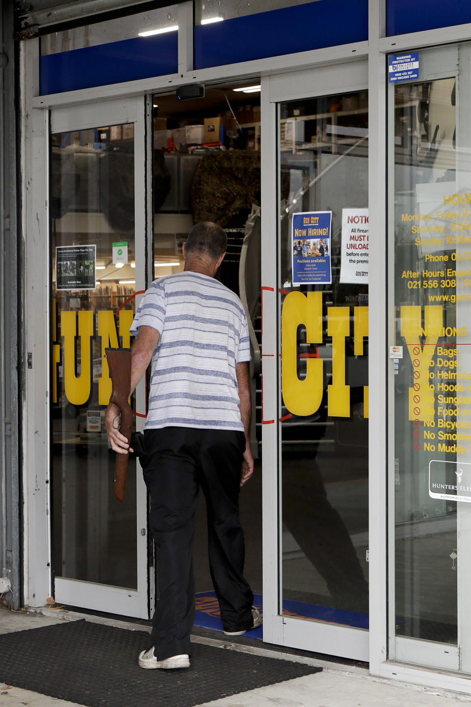 Ian Britton walks into a gun shop in Christchurch, New Zealand, Sunday, March 17, 2019. Gun ownership in New Zealand is being discussed after a mass shooting at two area mosques. (AP Photo/Mark Baker)
