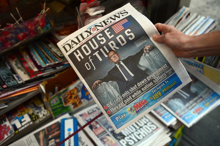 A woman buys a copy of the New York Daily News, featuring Speaker of the US House of Representatives John Boehner following, an US government shutdown in New York, October 1, 2013