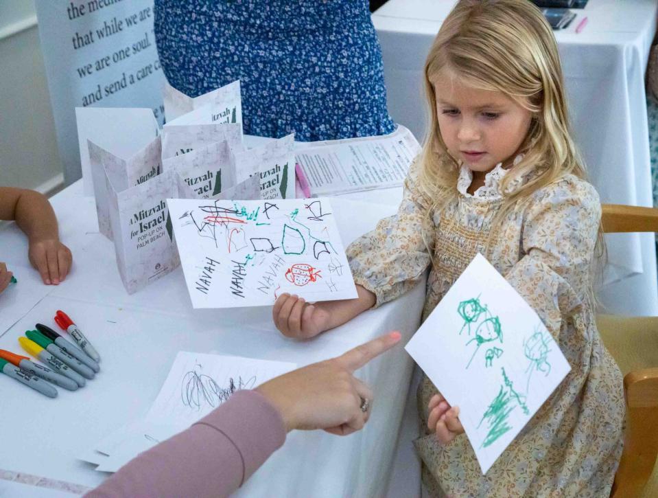 Navah Lipson, 4, holds up cards that she created to support and encourage soldiers at war in Israel during a "Mitzvah for Israel" pop-up store at The Chabad House Palm Beach October 12, 2023.