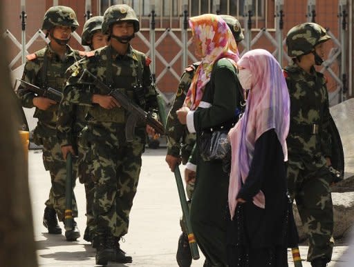 Muslim ethnic Uighur women pass a Chinese paramilatary police on patrol on a street in Urumqi, capital of China's Xinjiang region. Xinjiang has been under heavy security since July 2009, when Uighurs launched attacks on Han people -- who make up most of China's population -- in the regional capital Urumqi