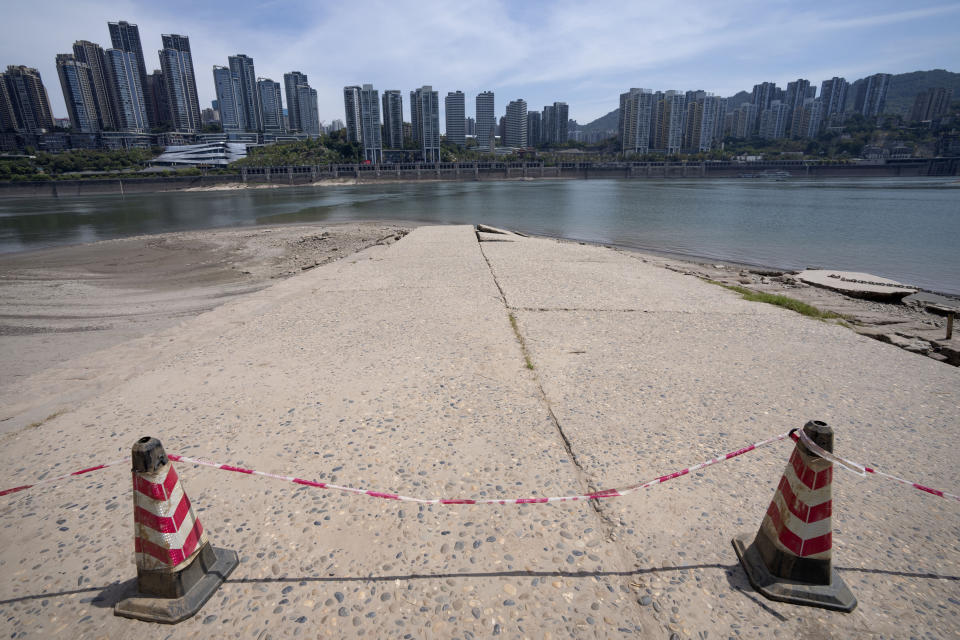 Cones and caution tape block a path leading to the Yangtze River in southwestern China's Chongqing Municipality, Friday, Aug. 19, 2022. Ships crept down the middle of the Yangtze on Friday after the driest summer in six decades left one of the mightiest rivers shrunk to barely half its normal width and set off a scramble to contain damage to a weak economy in a politically sensitive year. (AP Photo/Mark Schiefelbein)