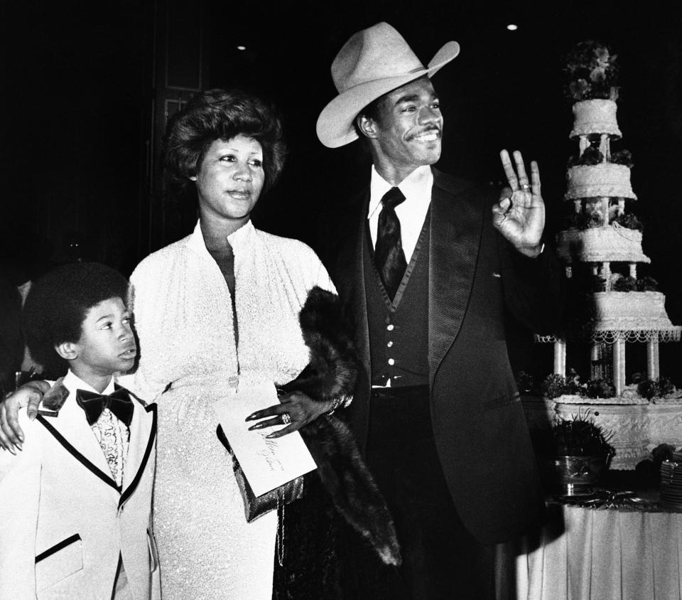 FILE - In this April 17, 1978 file photo, Aretha Franklin and her new husband, Glen Turman, arrive at a Los Angeles hotel for their wedding reception. Turman signals his okay and pleasure at the reception as Kecalf 8, Aretha's son looks on. Franklin died Thursday, Aug. 16, 2018 at her home in Detroit. She was 76. (AP Photo/Doug Pizac, File)