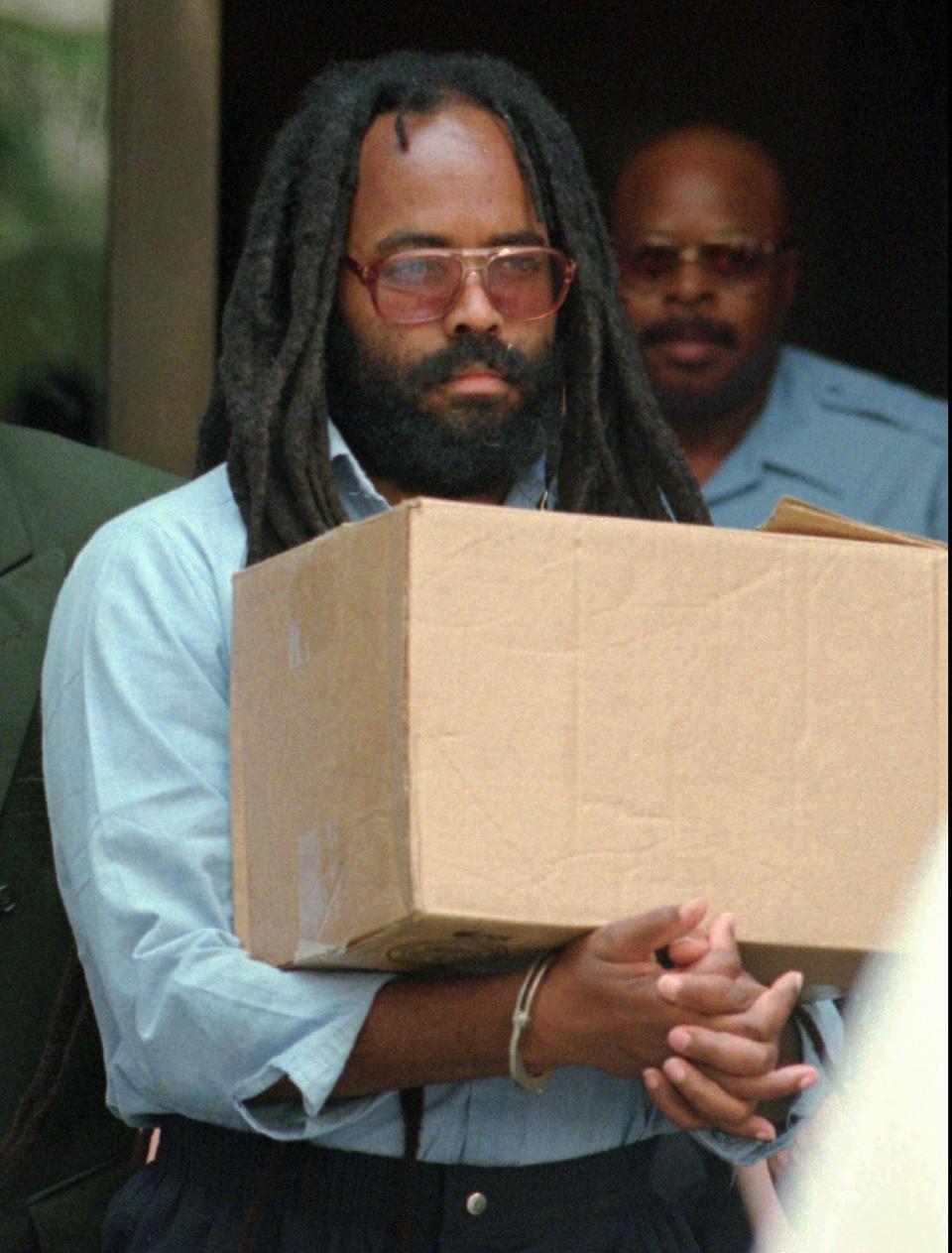FILE - In this July 12, 1995 file photo, Mumia Abu-Jamal leaves Philadelphia's City Hall after a hearing. Philadelphia is poised to revisit one of its most contentious murders as prison activist Mumia Abu-Jamal fights for another day in court in a 1981 police slaying. Police widow Maureen Faulkner fears she will never find closure in the criminal justice system after nearly 40 years. She filed a petition Thursday, Sept. 19, 2019 to get Philadelphia District Attorney Larry Krasner’s office recused from the case after Krasner failed to oppose Abu-Jamal’s bid for a new court hearing.(AP Photo/Chris Gardner, File)