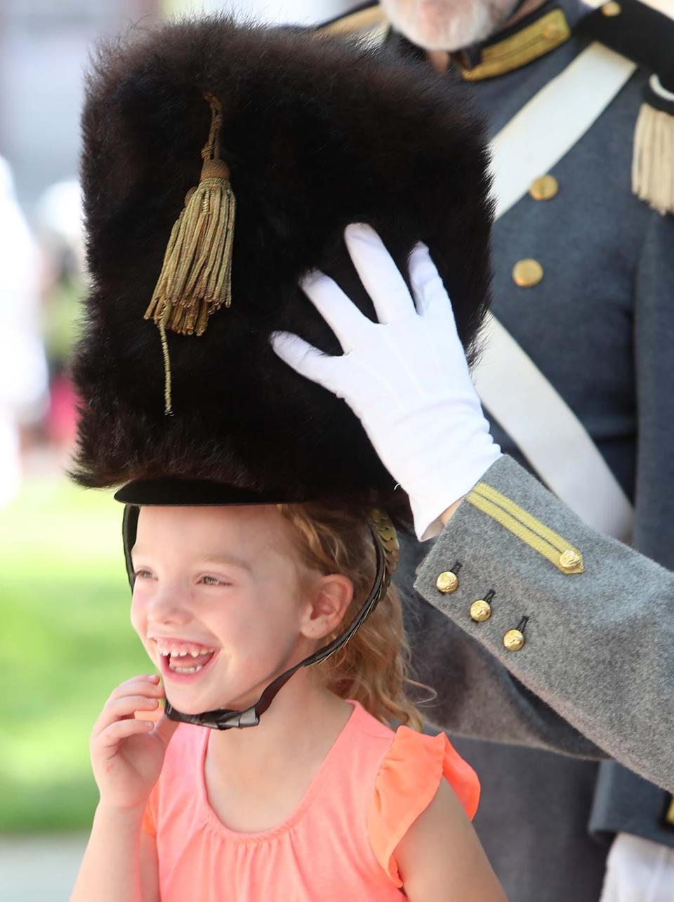 Leah Starkey, 6, of Medina, laughs as a toy soldier lets her try on his hat for a photograph.