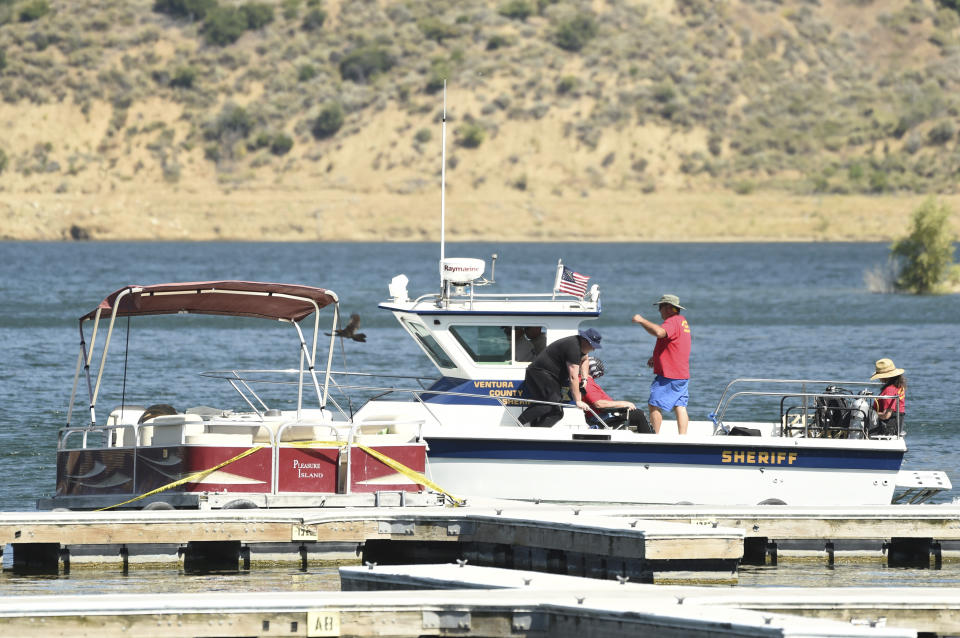 Members of Ventura County Sheriff's Office Underwater Search and Rescue Team search for former "Glee" actress Naya Rivera, right, as the boat Rivera rented on Wednesday appears surrounded by caution tape on Thursday, July 9, 2020, at Lake Piru in Los Padres National Forest, northwest of Los Angeles. Rivera's 4-year-old son was found alone on the rented boat. (AP Photo/Chris Pizzello)